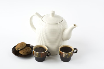Two ceramic cups of coffee with cookies on a dish and a ceramic
