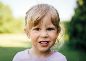 Adorable blond girl grinning looking at camera in the park