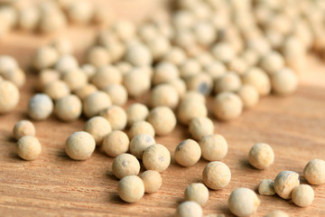 white pepper seeds on wooden background.