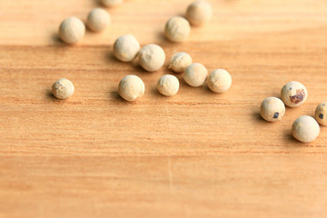 white pepper seeds on wooden background.