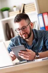 Obraz premium Young businessman looking at tablet in his office