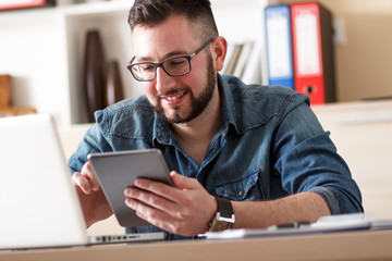 Young businessman looking at tablet in his office