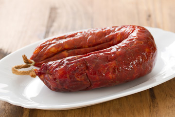 chourico on dish on white dish on brown wooden background