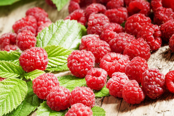 Fresh ripe raspberries with large leaves on the old wooden table