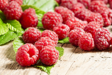 Fresh ripe raspberries with large leaves on the old wooden table