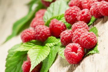 Fresh ripe raspberries with large leaves on the old wooden table