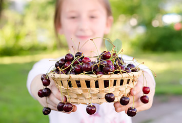 child holds a bowl with sweet cherries