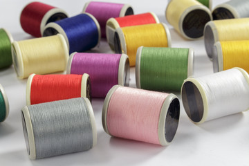 Close-up of bobbins of cotton thread for sewing machines; gray, pink and white threads in foreground