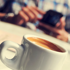 man with a cup of coffee using a smartphone in the terrace of a