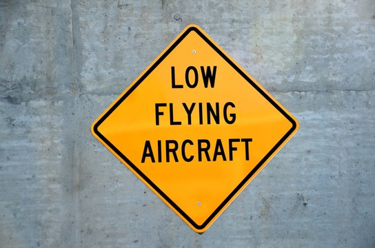 Low Flying Aircraft sign on cement wall background