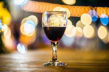 A glass of red wine on bokeh light background.