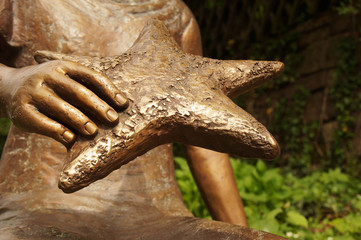 die zarte Hand einer Bronzefigur hält einen grossen 5 zackigen symbolisierten Stern. Ein Symbol...