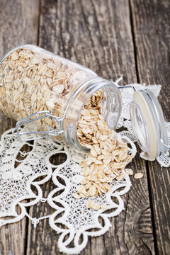 Oat flakes spilled out from jar on lace napkin.