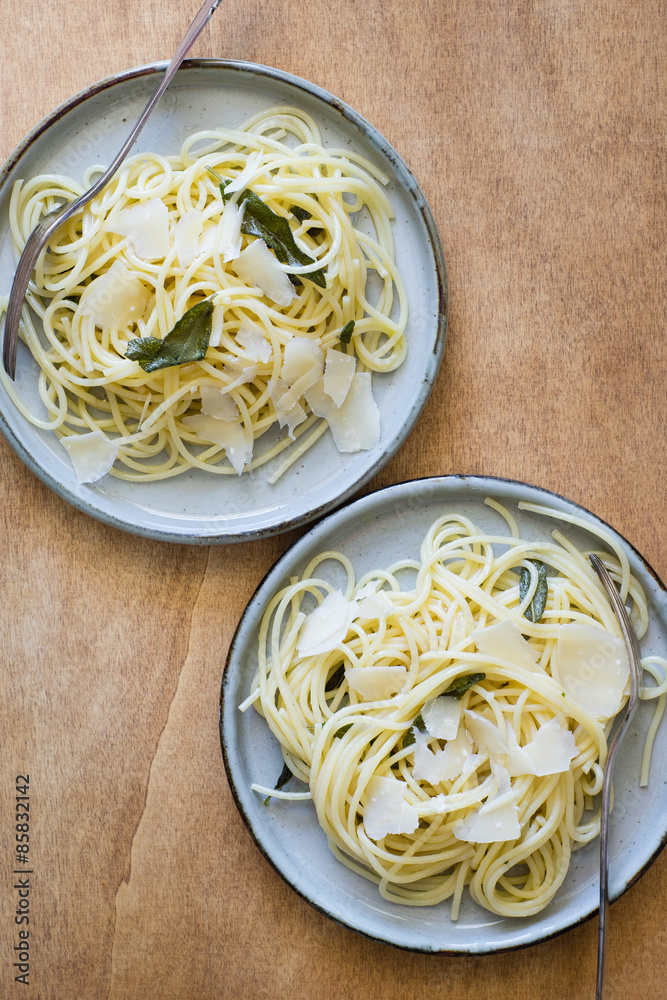 Wall mural two plates of spaghetti with butter and fried sage leaves served with parmesan shaves