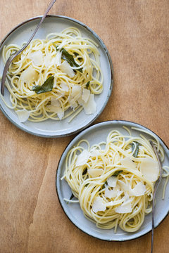 Two Plates of Spaghetti with Butter and Fried Sage Leaves Served with Parmesan Shaves