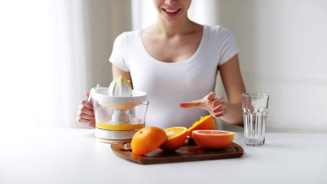 woman with squeezer squeezing orange juice at home
