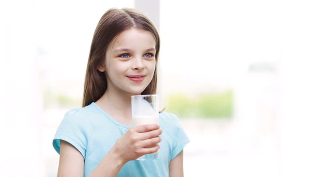 happy smiling little girl drinking milk at home