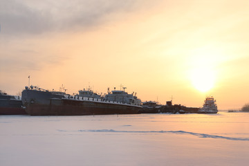 Big rusty ship in frozen river in evening winter evening 