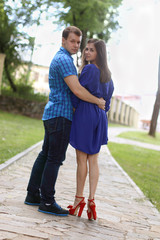 Young woman and man in blue stand on path in summer green park