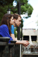 Fototapeta premium Young man and woman stands near railing near small river in park