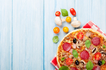 Italian pizza with pepperoni, tomatoes, olives and basil