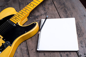 Telecaster electric guitar with notepad on wood desk
