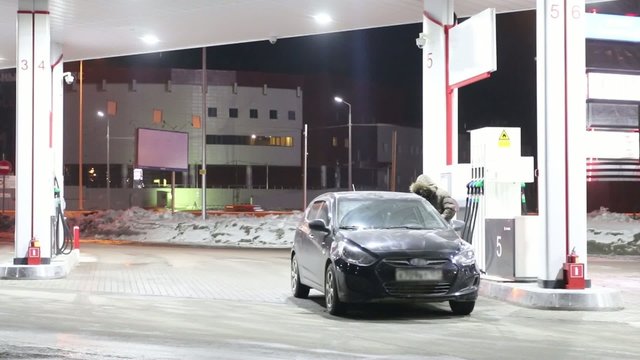 Man refuels his car on petrol station and leaves at night in winter. Time lapse
