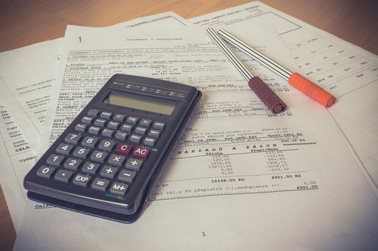Business composition of bills, calculator, pen and various statistics on the table