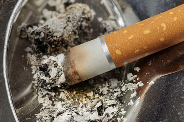 Cigarette and ashes in a metal ashtray