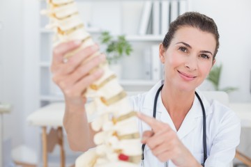 Happy doctor showing anatomical spine