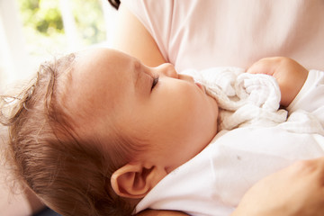 Obraz na płótnie Canvas Mother Holding Sleeping Baby Boy At Home