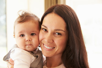 Mother Cuddling Happy Baby Boy At Home