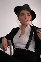 beautiful young woman in a stylish black suit and white blouse and hat Smoking a pipe