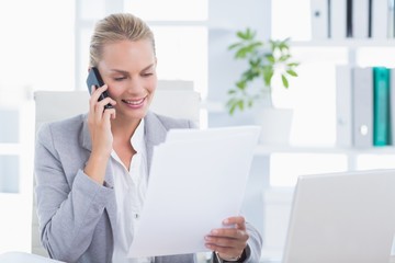 Smiling businessman phoning at her desk 