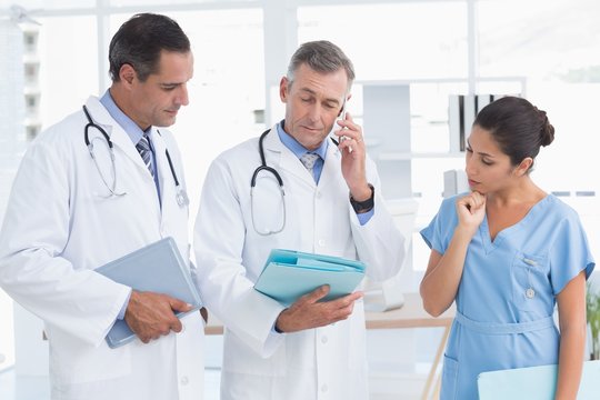 Doctor having phone call while his colleague speaking 