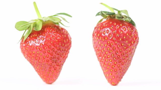 Two strawberries rotating in a seamless loop (each around its own axis) on white background, close up shot
