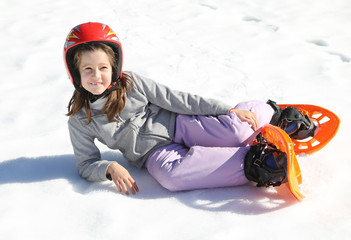 pretty girl with orange snowshoes on snow in winter