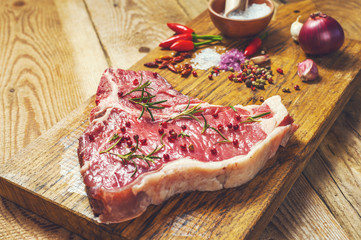 Close-up of fresh meat steak with spices on wooden background