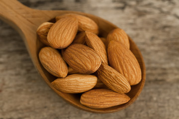 peeled almonds in spoon on wooden background. For vegetarians