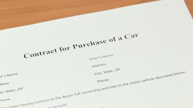 Car Buyer Signature - Female signing a contract for purchase of a car, closeup of a car buyer signature on a blank car sales document