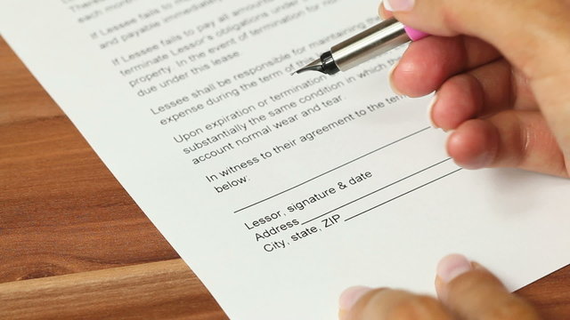 One person signs a lease contract on a rental property