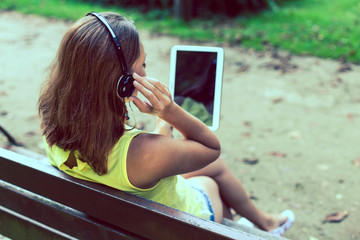 Young girl looks see a tablet in the park