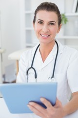 Smiling doctor looking at camera with tablet pc 