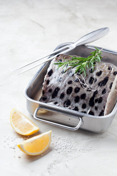 Slice of fresh fish (Wolffish) in a metal baking dish, selective focus