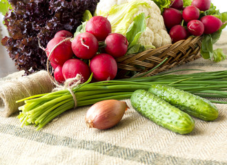 Basket with vegetables: lettuce, cucumbers, onions, chives, cauliflower, radish