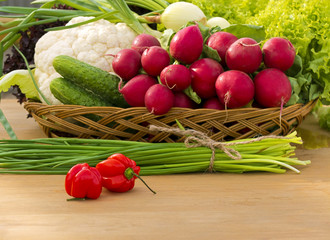 Basket with vegetables: lettuce, cucumbers, onions, chives, cauliflower, radish