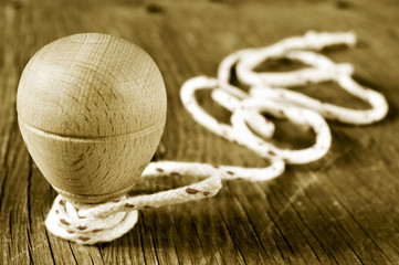 wooden spinning top with a string coiled in its axis, in sepia t