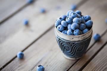 Old bowl of fresh organic blueberries on wooden table