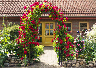 Fototapeta na wymiar Romantischer Vorgarten mit Rosenbogen