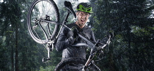 Naklejka premium Nasser Mountainbiker mit Fahrrad auf der schulter